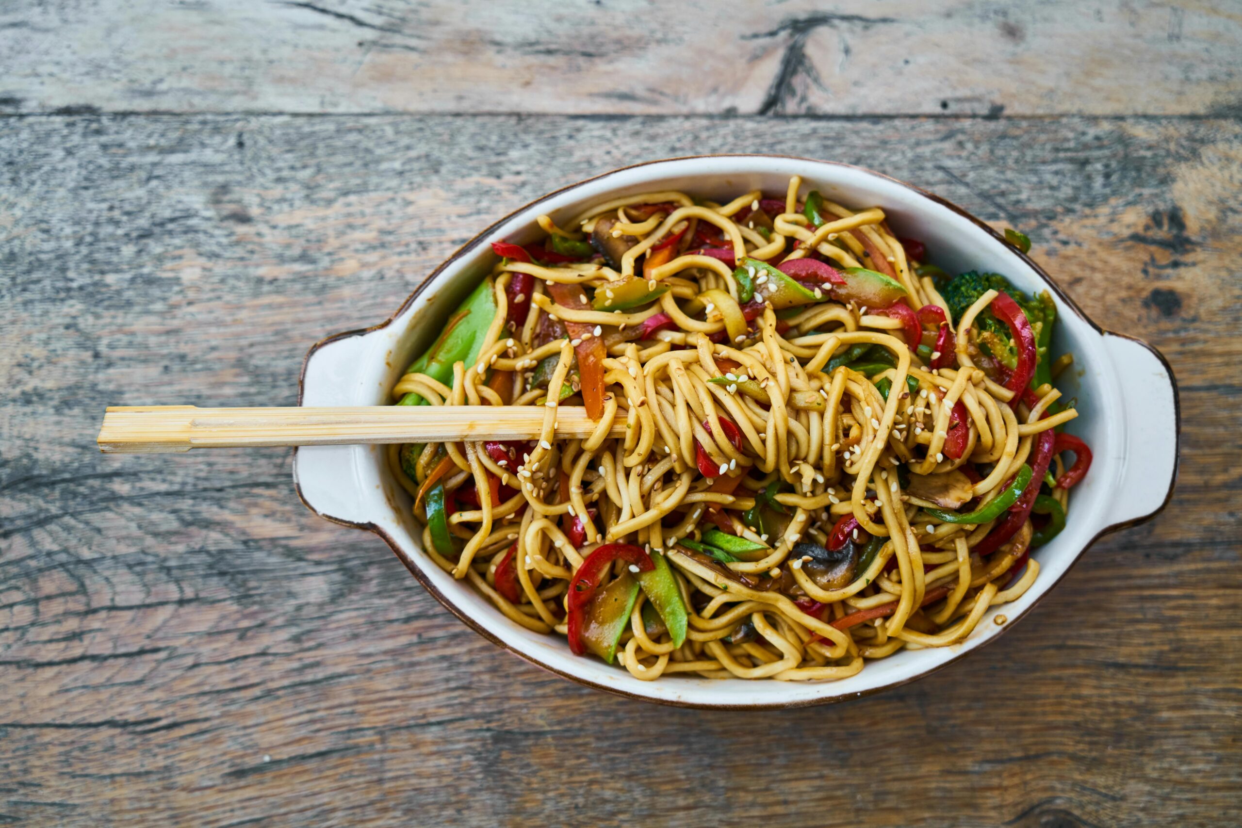 A bowl of stir-fried noodles with vegetables, showcasing a complex carbohydrate-rich meal that supports metabolism and fat loss.